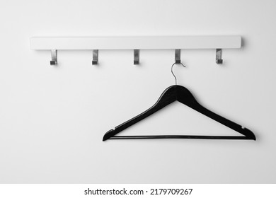 Rack With Empty Black Clothes Hanger On White Wall