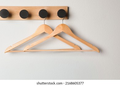 Rack with empty wooden clothes hangers on white wall