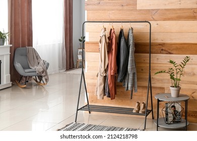 Rack With Female Outwear Clothes And Shoes Near Wooden Wall