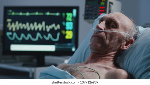 Rack focus shot from heart monitor to sleeping elderly male patient - Powered by Shutterstock