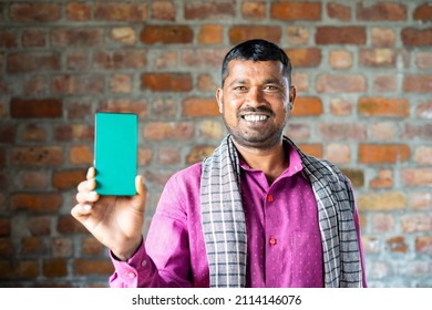 Rack Focus Shot Of Indian Daily Wager Showing Green Screen Mobile Phone By Looking At Camera - Concept Of Technology, Blue Collar Job, Advertisment And Promotion.