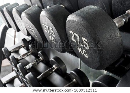 A rack of heavy dumbbells with weight labels in kilograms at the gym. Weight training equipment.