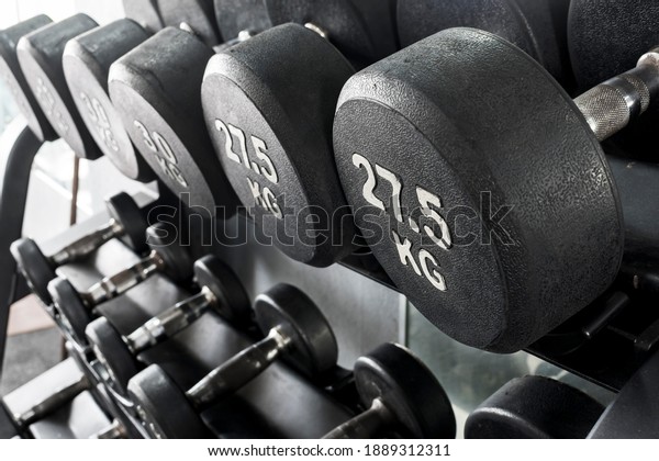 A rack of heavy dumbbells with\
weight labels in kilograms at the gym. Weight training\
equipment.