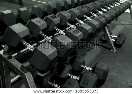 A rack of heavy hex dumbbells at a gym or fitness club. Workout and pyramid training or running the rack for serious bodybuilding concept.