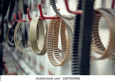 A rack of industrial machine drive bets hanging in an industrial factory. Drive belts and cam belts for machinery and automobiles. Drive belts engage machine cogs to power and drive efficiency. 