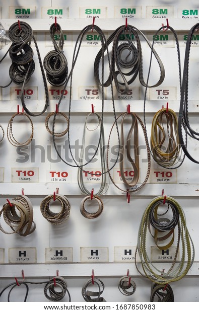 A rack of industrial machine drive bets hanging in an\
industrial factory. Drive belts and cam belts for machinery and\
automobiles. Drive belts engage machine cogs to power and drive\
efficiency. 