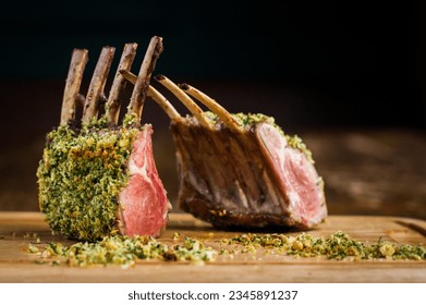 Rack of lamb with hazelnut herb crust on wooden board in restaurant