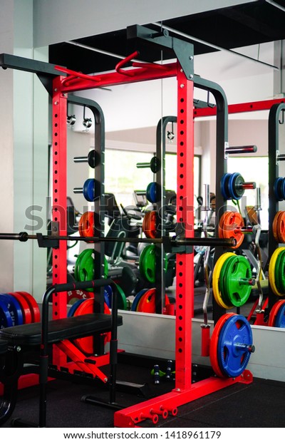 rack\
squat, barbell and weight plates, various sizes, beautiful colors\
Was kept neatly in the gym To prepare for exercise In the gym,\
there are many equipment for functional\
exercises.