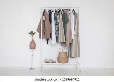 A Rack With Stylish Clothes Next To A White Wall In The Room. Clothing Retails Concept. Advertise, Sale, Fashion.