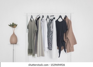 A Rack With Stylish Clothes Next To A White Wall In The Room. Clothing Retails Concept. Advertise, Sale, Fashion.