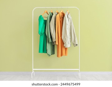 Rack with stylish female clothes against green wall - Powered by Shutterstock