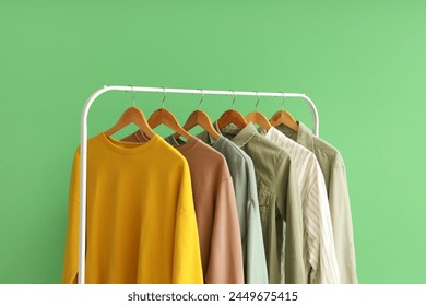 Rack with stylish female clothes near green wall, closeup - Powered by Shutterstock