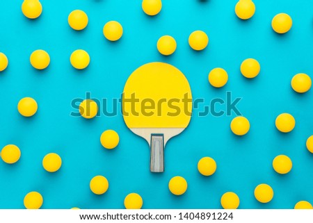 racket and many balls for table tennis on turquoise blue background. flat lay image of many table tennis balls with tennis paddle in the middle. minimalist photo of yellow ping-pong equipment