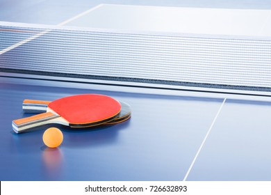 Rackets and ball on the blue tennis table. Indoor sport activity. Sport concept.