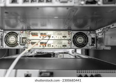Rackmount chassis with installed two-unit server in datacenter, rear view from power supply units. Selective focus.