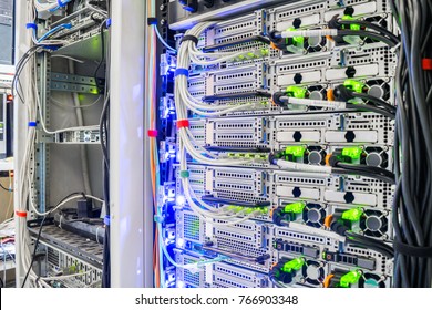 Racks with server equipment are located in the data center. Mining bitcoins and crypto currency. A bundle of network wires connects to the computer interfaces