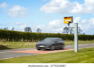 Radar speed camera and fast speeding car on the road in the UK