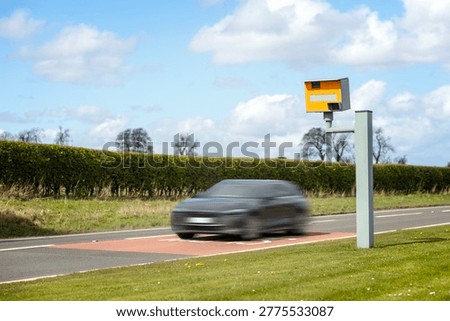 Radar speed camera and fast speeding car on the road in the UK