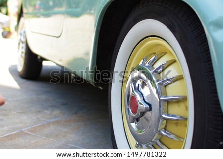 Radial whitewall vintage tire on a vintage car. A black tire with a white stripe on a nice and shiny steel rim. 