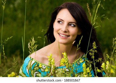 Radiant Beautiful Woman With A Happy Serene Expression Standing Outdoors In Nature Amongst Fresh Green Spring Leaves With Her Face Tilted To The Sunshine