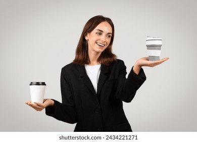 A radiant caucasian young woman in business attire joyfully balances two coffee cups, one on her hand and another levitating above her palm, suggesting a busy yet manageable lifestyle - Powered by Shutterstock