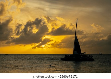 A radiant golden sunset casts shimmering light across calm waters. Silhouetted sailboats gently drift, their dark forms contrasting with the fiery hues of the sky, evoking serenity and wonder. - Powered by Shutterstock