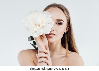 Radiant Skin, Tenderness And Health. Beautiful Girl Covers The Face Of A Delicate White Flower On A White Background. Spa, Beauty Salon.