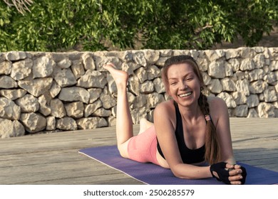 A radiant and smiling red-haired young woman relaxes on her mat after an outdoor yoga and Pilates session. The sun illuminates the scene, well-being and serenity. - Powered by Shutterstock