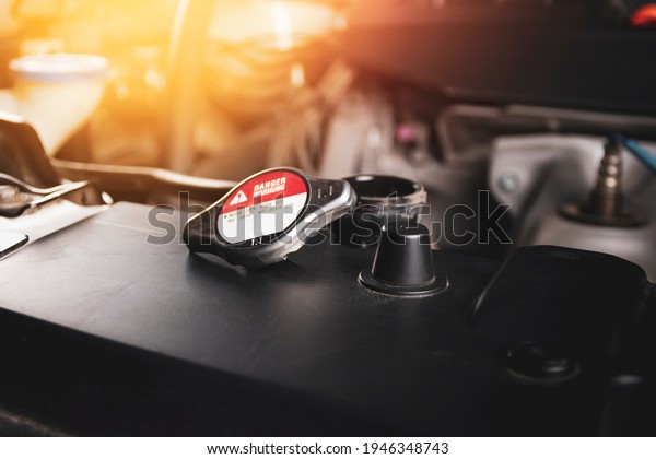 The radiator cap 1.1 bar is open\
and placed on radiator of the car engine with a\
sunlight