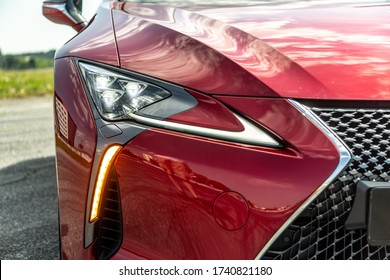 Radiator grill and headlight on a red car on a sunny day. Close-up. Horizontal orientation.