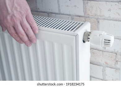 Radiator for home heating. Water heating. Hands of a man on the radiator.