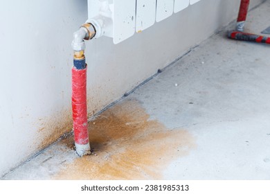 Radiator pipe wrapped in red electrical tape, heating leak, rusty puddle on floor Breakdown of heating system in apartment, insured , flooding of neighbors Turnkey repair service, plumbing replacement