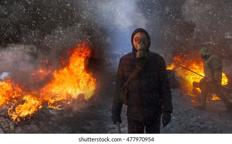 Radical Protestant in the mask represents the protesters against the authorities among the burning of the capital of the European quarter. Burning rubber tires wheel of fire smoke soot street fighting