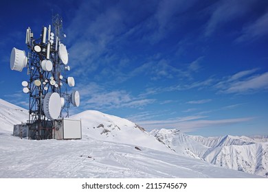 Radio aerial antenna mast with a lot of satellite dishes, parabolic reflector or dish antennas for microwave communications links on communication tower among snowy mountains
