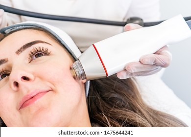 Radio Frequency Microneedling Machine Handpiece On The Cheek Of A Woman's Face During A Beauty Skin Tightening Treatment.