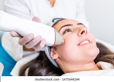 Radio Frequency Microneedling Machine Handpiece On The Cheek Of A Woman's Face During A Beauty Skin Tightening Treatment.