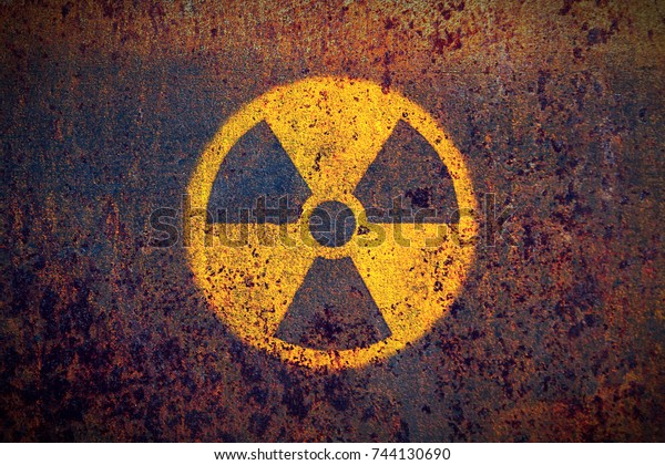 Radioactive (ionizing radiation) round yellow\
and black danger symbol painted on a massive rusty metal wall with\
dark rustic grunge texture background. Nuclear, radioactive alert\
concept.