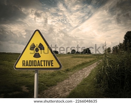 Radioactive pollution. Yellow warning sign with hazard symbol near contaminated area outdoors. Space for text