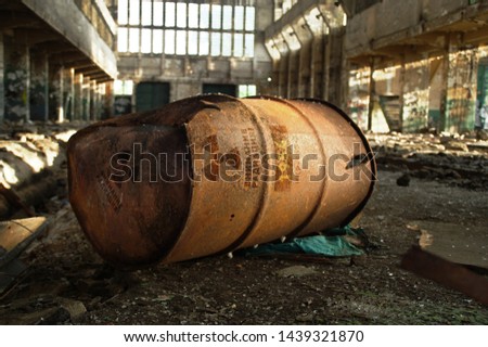 Radioactive warning on old rusty barrel in destroyed and forgotten building. Radiation symbol with russian alert on waste container after nuclear disaster.