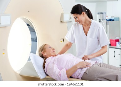 Radiologic technician smiling at mature female patient lying on a CT Scan bed