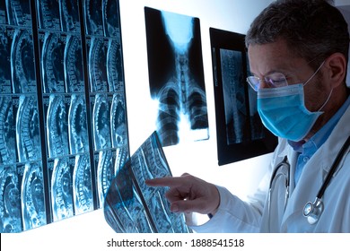 Radiologist doctor with face mask examining spinal column by radiography, x-ray and magnetic resonance imaging scan in hospital. Medical check-up and diagnosis. Health care concept.