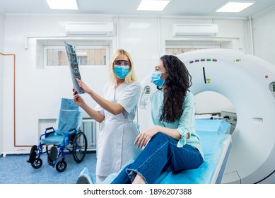 Radiologist With A Female Patient Wearing Protective Masks Examining A CT Scan