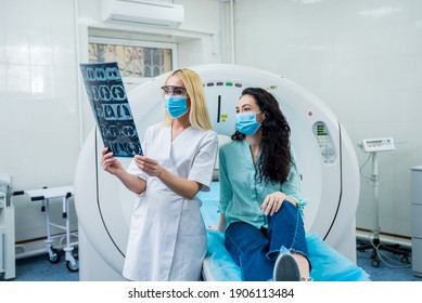 Radiologist With A Female Patient Wearing Protective Masks Examining A CT Scan