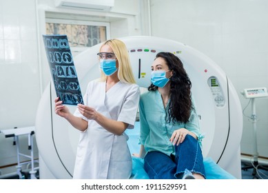 Radiologist With A Female Patient Wearing Protective Masks Examining A CT Scan