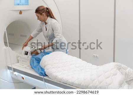 a radiologist in a medical clinic puts the device on the patient's head before brain magnetic resonance imaging procedure