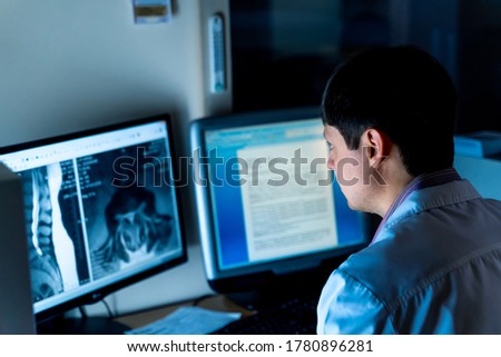Radiologist sitting at computer in office. X-ray picture on screen. Healyj care concept.