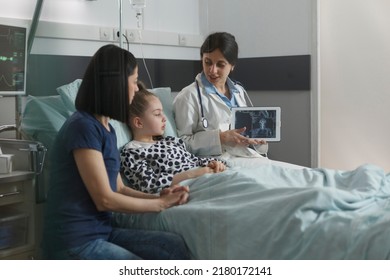 Radiology Expert Examining Radiography Scan Image Of Sick Little Girl Resting In Hospital Pediatric Ward. Radiologist Showing Xray Scanning Result Of Under Treatment Kid Brain Condition.