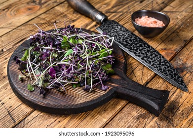 Radish microgreens, green leaves and purple stems. Wooden background. Top view