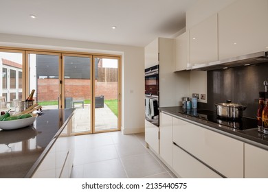 Radwinter, Essex - Sept 12 1018: Modern Furnished New Kitchen With Peninsular Island, Granite Worktops And Bifold Doors Leading To Patio And Garden