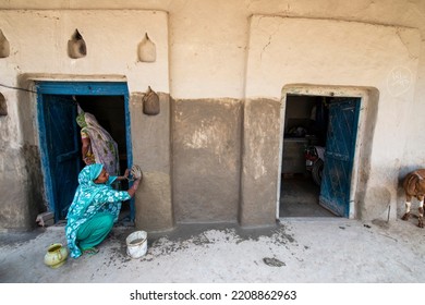 Raebareli; Uttar Pradesh, India-Aug 7 2015: Indian Women Cleaning The House Front With Cow Dung, A Village Life In Raebareli. Woman Repairing House Wall With Mud And Cow Dung Mixture